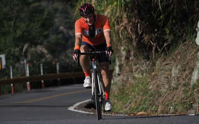 Cyclist climbing a mountain road through lush green hills in Taiwan