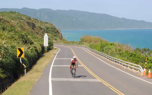 Cyclist riding along the turquoise coastal road in Kenting National Park, Taiwan