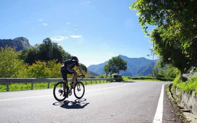 Cyclist riding through Taiwan's East Coast Rift Valley with mountain peaks ahead
