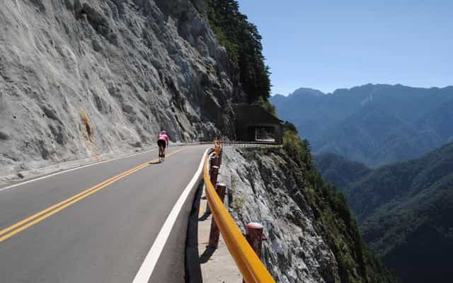 Cyclist riding along the cliff-edge road through Taroko Gorge, Taiwan