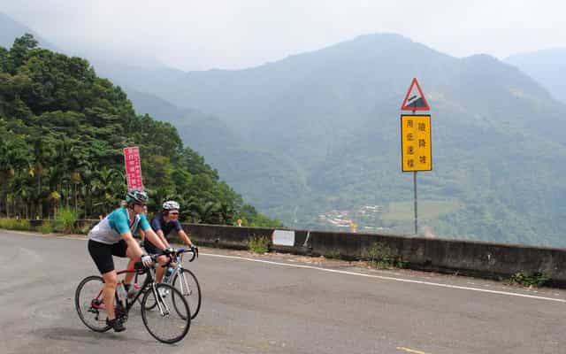 Two cyclists climbing a mountain road near Puli, Taiwan