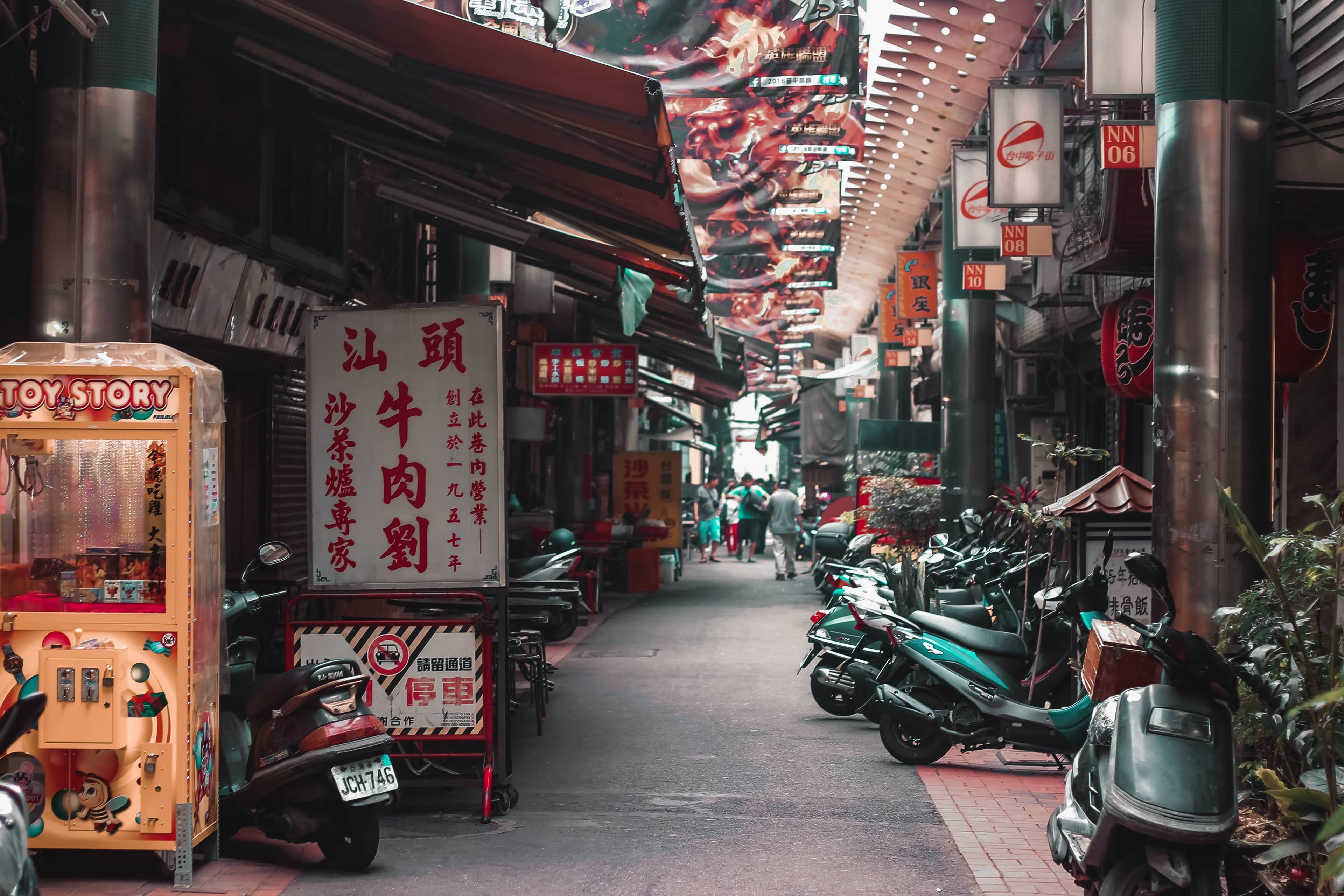 A narrow street in Taiwan lined with traditional shophouses, Chinese signage, food stalls, and scooters, the layered culture of an island shaped by centuries of history