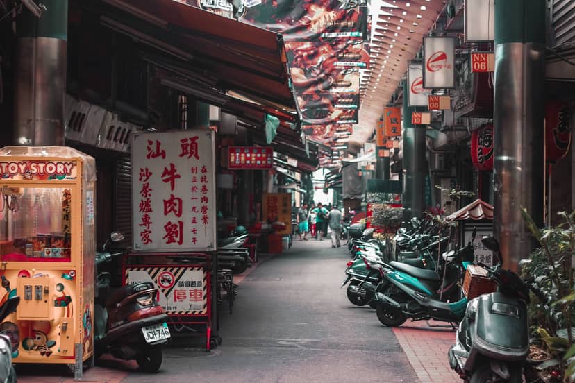 A narrow street in Taiwan lined with traditional shophouses, Chinese signage, food stalls, and scooters, the layered culture of an island shaped by centuries of history