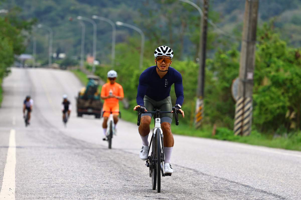 Cyclist on a rural Taiwanese road being followed at a distance by the support vehicle