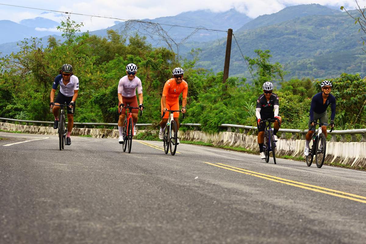 Five cyclists riding together on a mountain road in the East Rift Valley, matching pace as a group