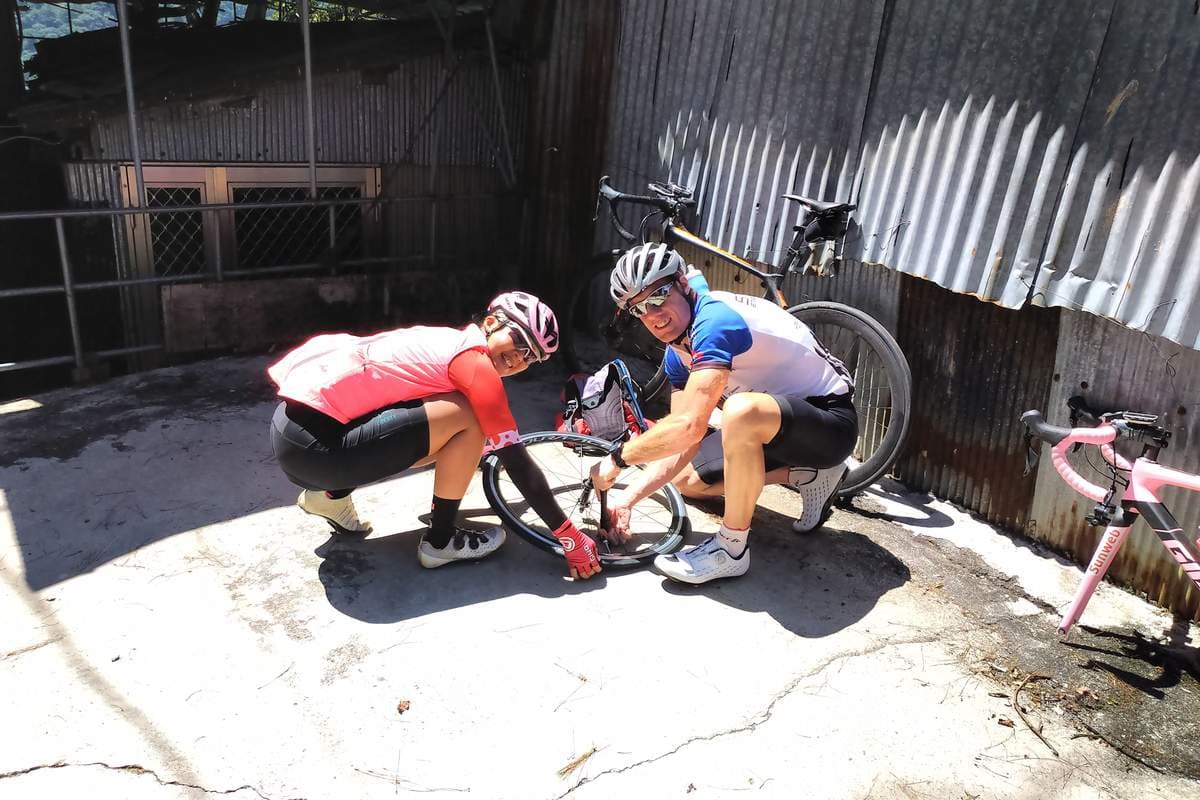 Two cyclists in helmets examining a road bike together at the start of a tour, checking the build before riding