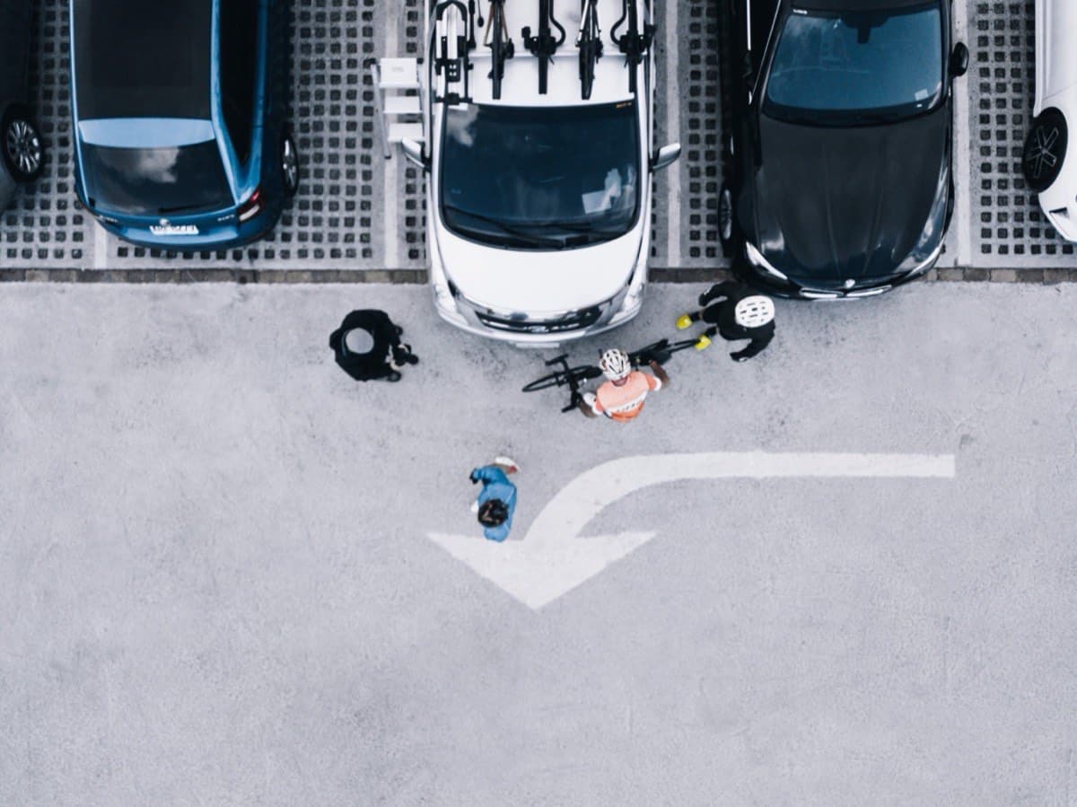 Aerial view of Pedal Taiwan's support vehicle with bike rack in a car park, cyclists preparing their bikes before a ride