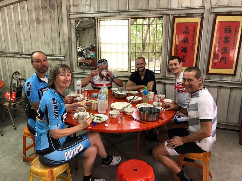 A tour group sharing a meal at a red table on a Pedal Taiwan tour