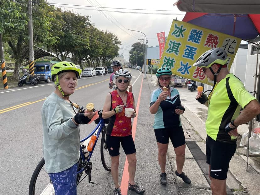 A group of cyclists on a refreshment break with a Pedal Taiwan guide on a roadside stop